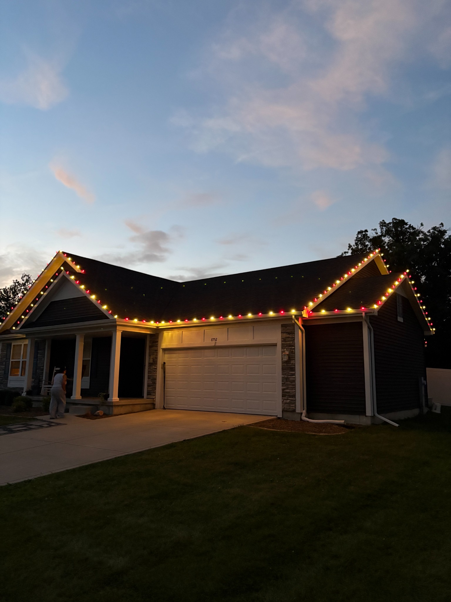 Custom red and warm white Christmas lights installed along a residential roofline